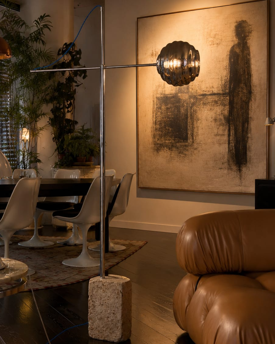 No. 006, Axis, a sculptural floor lamp with a rough rectangular base, tall upright, long crossbar, glowing dark ribbed shade, and visible blue cable.