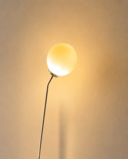 Partial photograph of No. 003, Halo, showing a glowing white globe on an angled slender stem; the lower lamp is outside the frame.