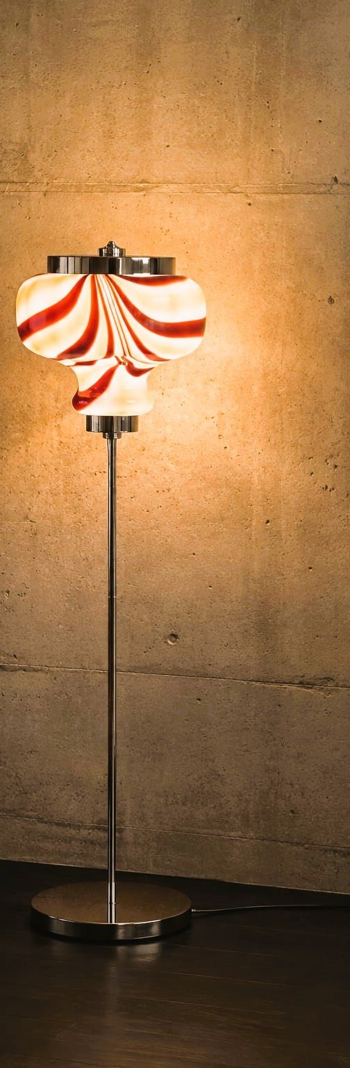 No. 038, Peppermint, an hourglass glass shade, swirled red and white, glows atop a slim chrome stem.